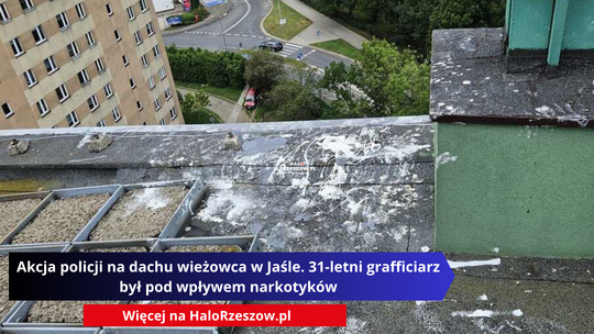 Widok z dachu wysokiego bloku na ulicę i budynki. Na pierwszym planie widać zanieczyszczenia z farby na dachu.