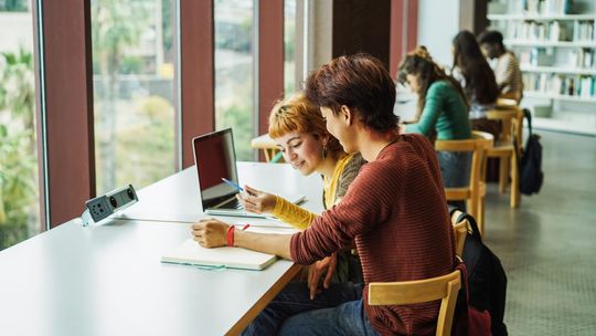 studenci przy biurku w bibliotece