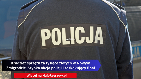 Zbliżenie na plecy policjanta w granatowej bluzie polarowej z dużym, białym napisem POLICJA. W dolnej części obrazu znajduje się czarno-niebieski pasek z nagłówkiem: „Kradzież sprzętu za tysiące złotych w Nowym Żmigrodzie