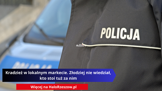 Główny plan na mundur policjanta z białym napisem POLICJA, w tle rozmyty policyjny radiowóz.