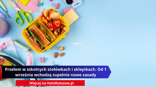 Widok z góry na otwarty, żółty pojemnik śniadaniowy wypełniony zdrową żywnością, leżący na błękitnym tle. Wewnątrz pojemnika znajduje się kanapka, owoce (pokrojone truskawki, jabłka) oraz orzechy. Wokół bento boxu rozsypane są przybory szkolne: ołówki, linijka, nożyczki, spinacze biurowe i notesy.