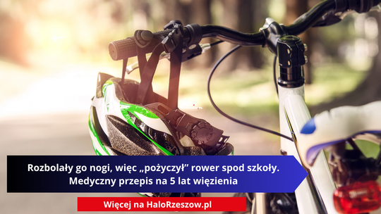 Zbliżenie na biały rower w nasłonecznionym parku z zawieszonym na kierownicy zielono-białym kaskiem. Na zdjęciu umieszczono napis: „Rozbolały go nogi, więc „pożyczył” rower spod szkoły. Medyczny przepis na 5 lat więzienia” oraz czerwony pasek na dole z adresem portalu Więcej na HaloRzeszow.pl.