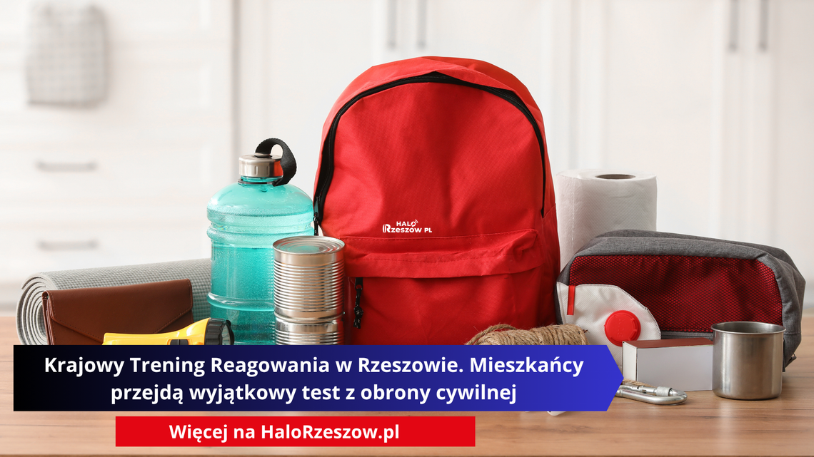 Czerwony plecak otoczony przedmiotami pierwszej potrzeby: butelką wody, puszkami jedzenia, latarką, apteczką, maską ochronną i ręcznikiem papierowym, leżącymi na drewnianym blacie.